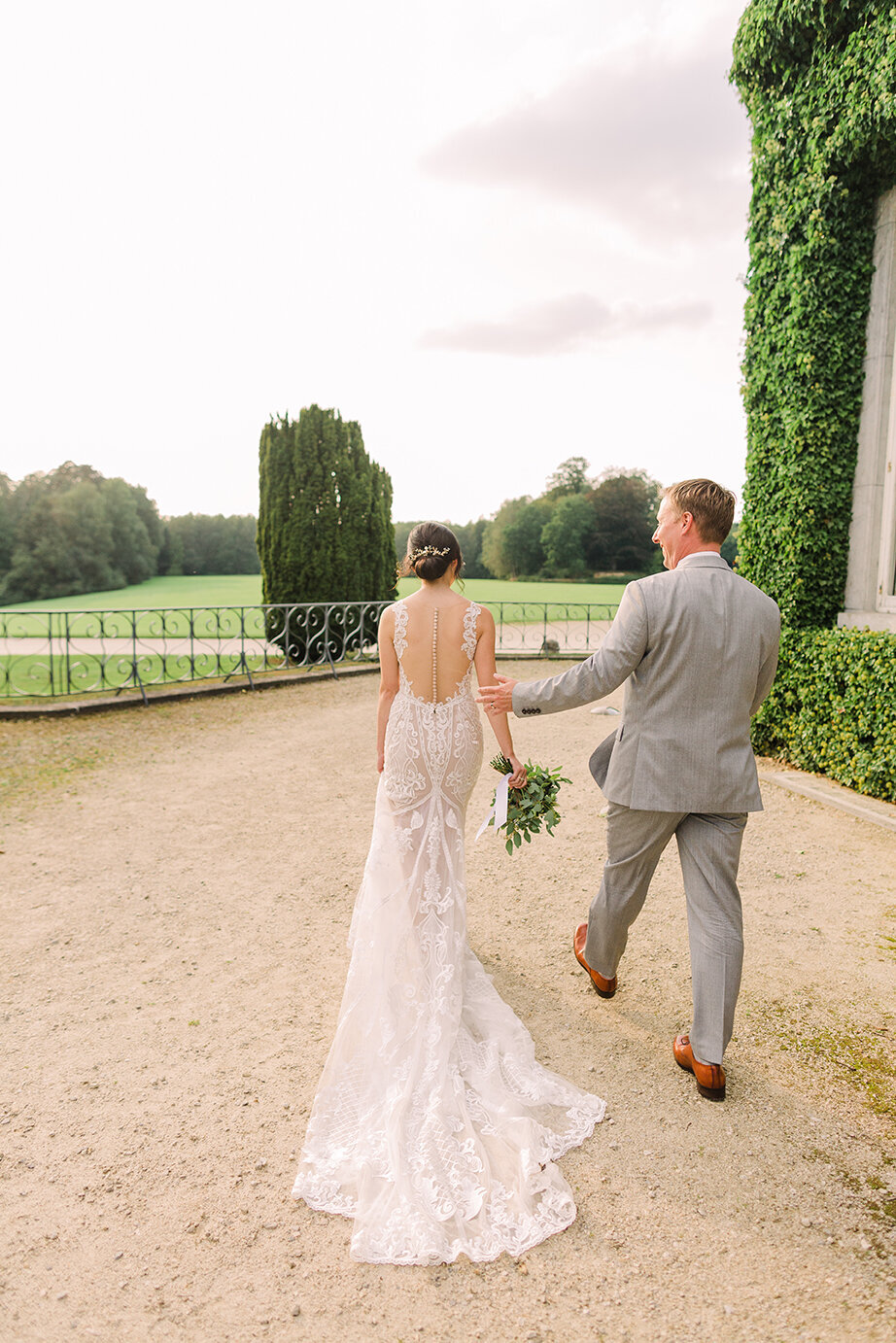 A dreamy wedding photo of a couple walking hand in hand into the sunset at a picturesque chateau in Belgium, creating a fairytale moment.