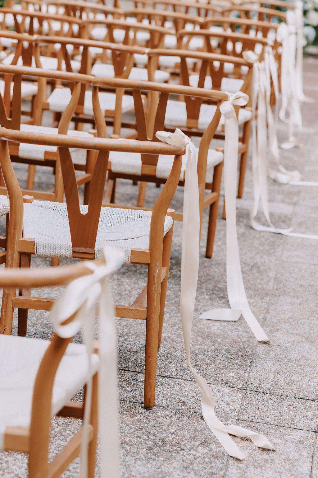 wishbone chairs with ivory ribbons tied to them