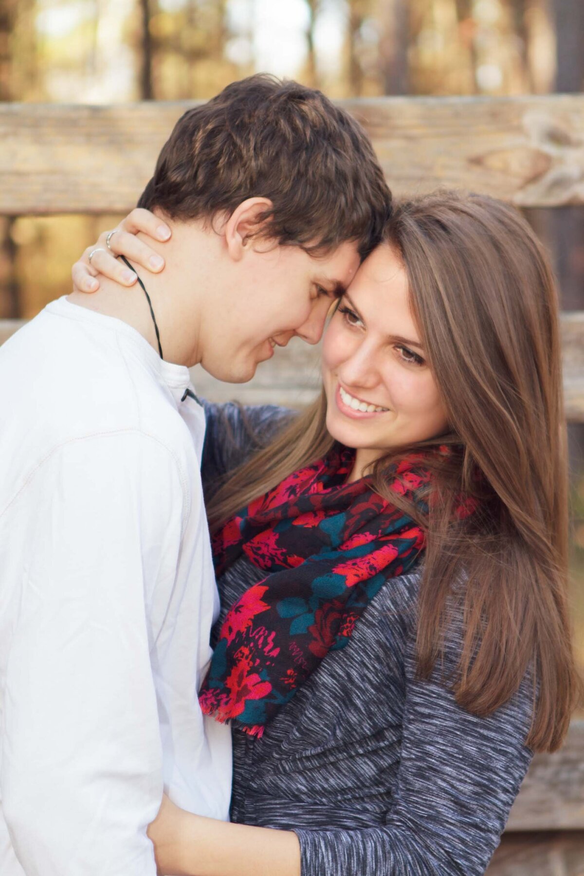 Woman in the arms of her fiance while she looks off into the distance smiling.