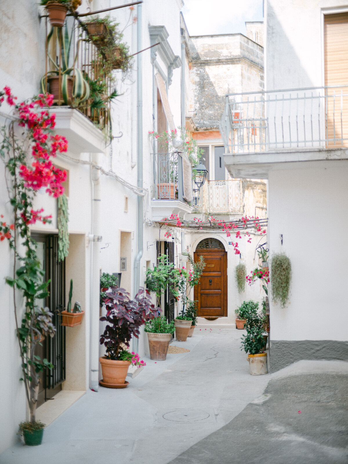 Charming Italian village street in Puglia with flowers and historic houses – perfect backdrop for romantic Italy wedding portraits.