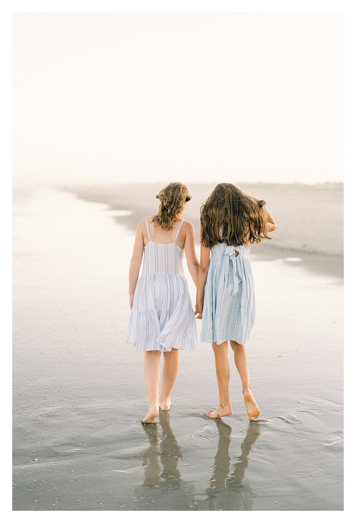 Two sisters walk the beach holding hands