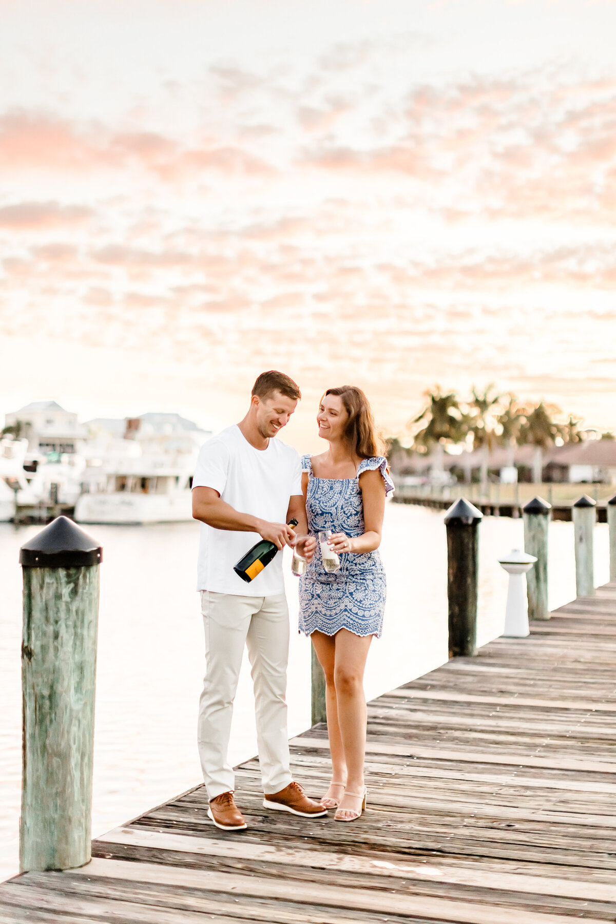 engaged couple enjoying champagne on a dock by wedding photographers fort myers