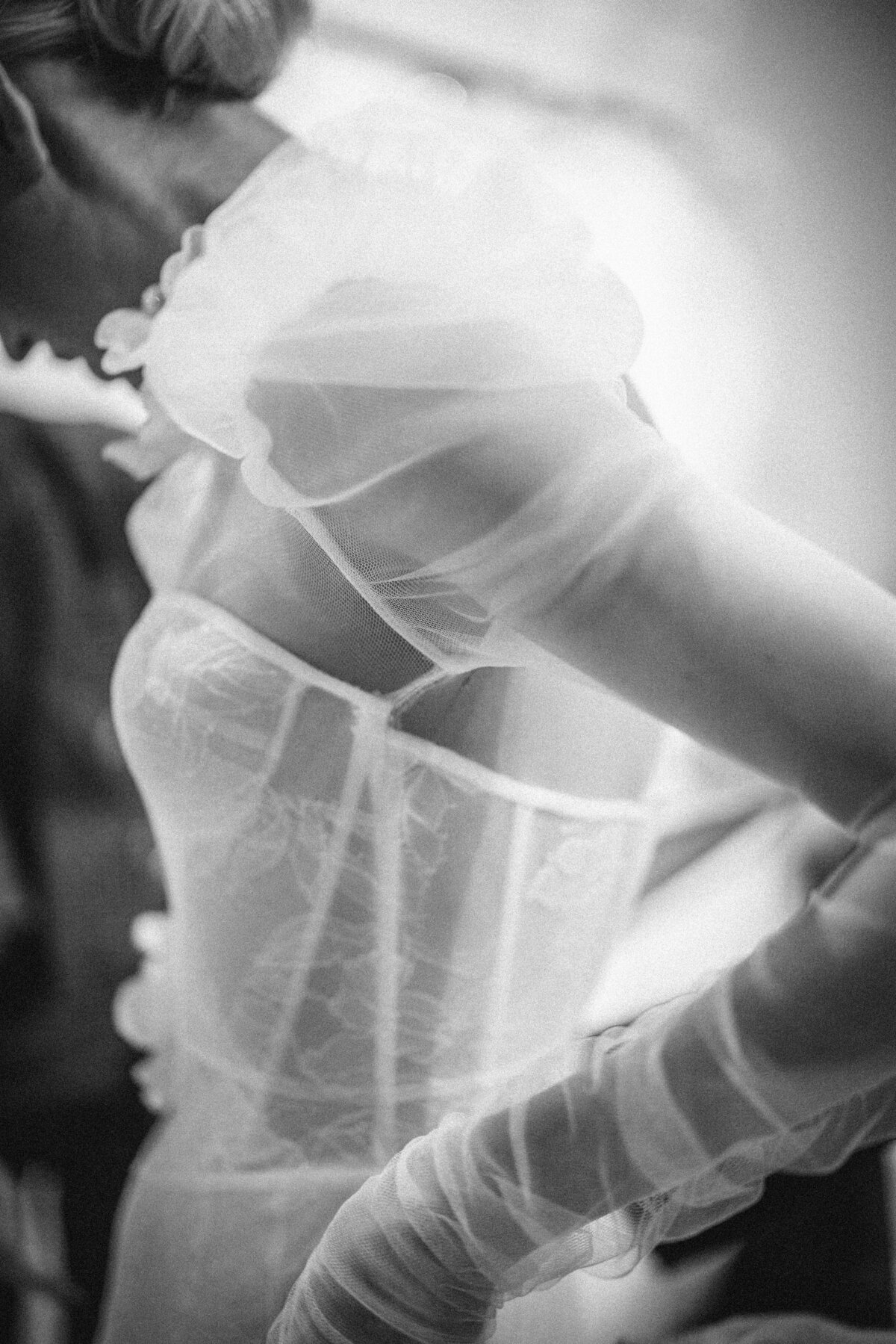 A black and white close-up of a bride wearing a sheer, lace dress with puffed sleeves. This photo was taken by a destination wedding photographer for luxury celebrations