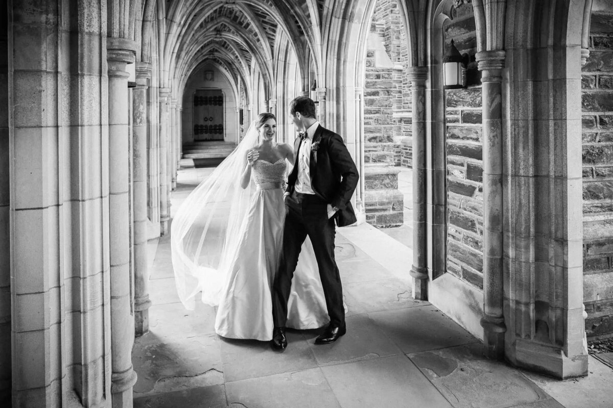 Bride and groom walking through the gothic archways of Duke Chapel