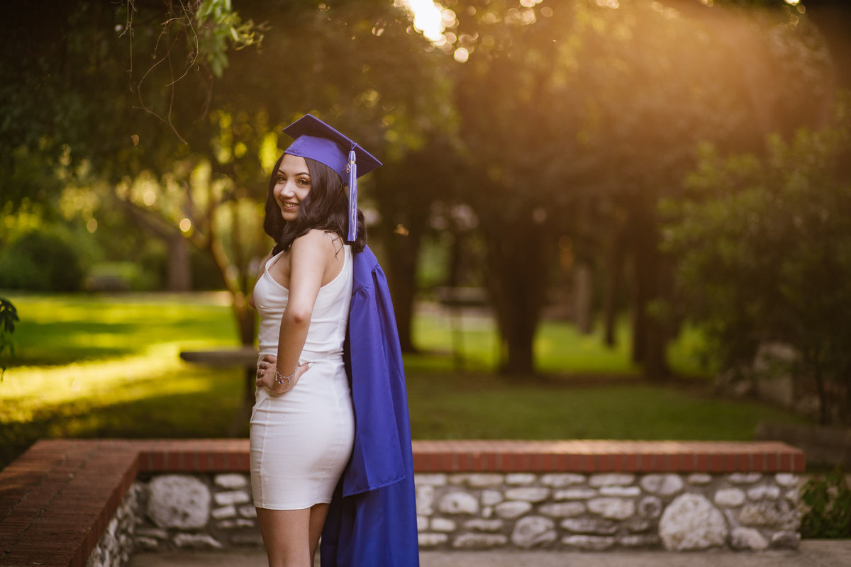 senior girl in high school graduation gown thrown over shoulder by San Antonio senior photographer
