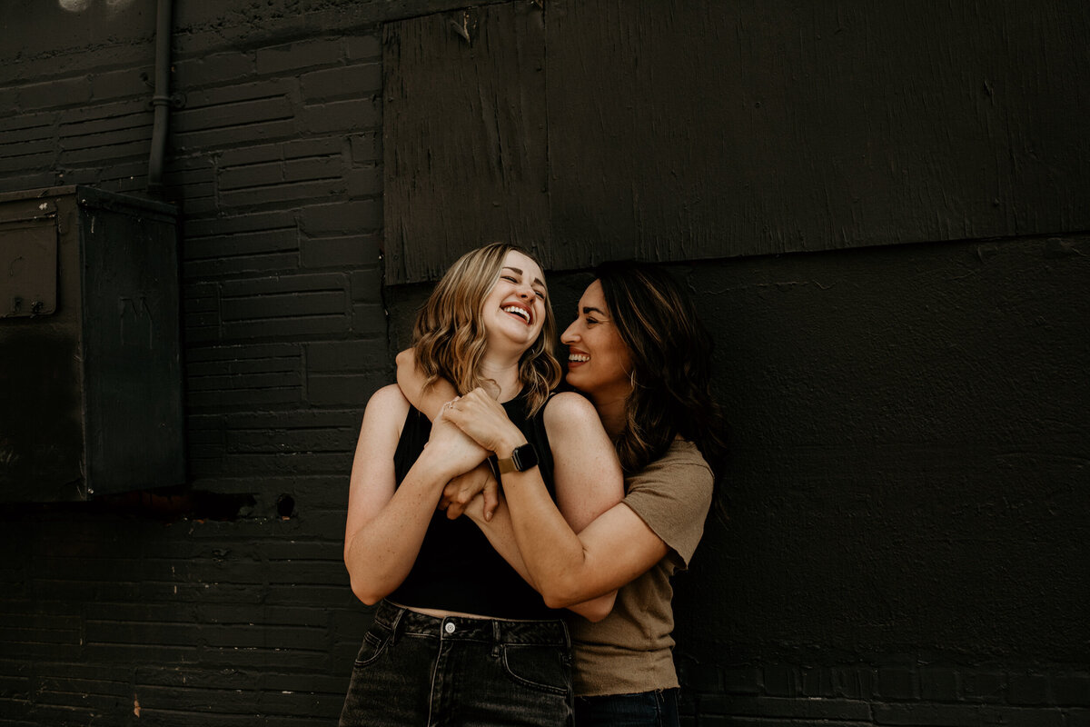 same sex couple hugging each other and laughing in an alley in downtown Albuquerque