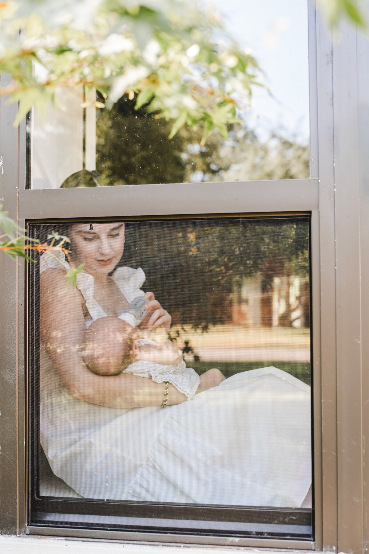 peeking inside a window at mom feeding baby