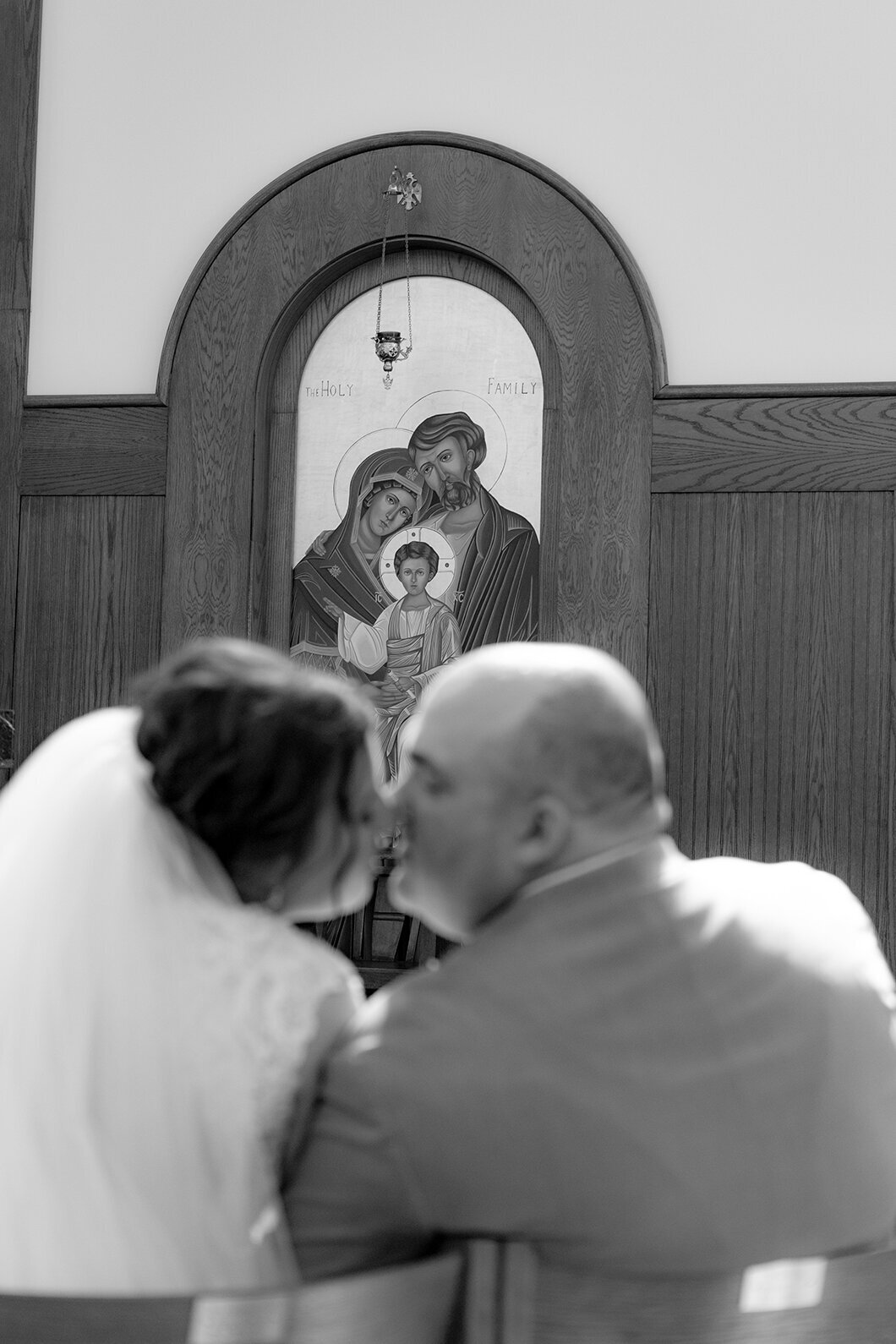 bride-and-groom-kiss-in-front-holy-family-icon