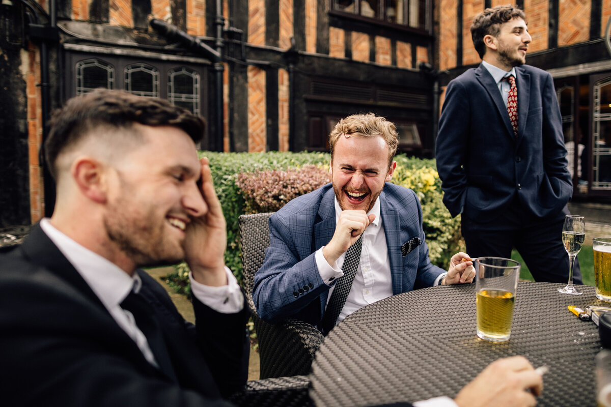 Grooms men laughing and sharing drinks at wedding