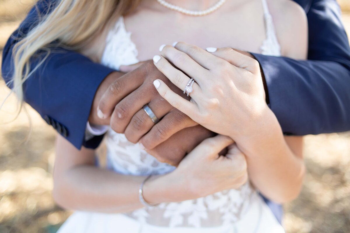 top raleigh nc wedding photographer capture of bride and groom hugging showing off their wedding rings