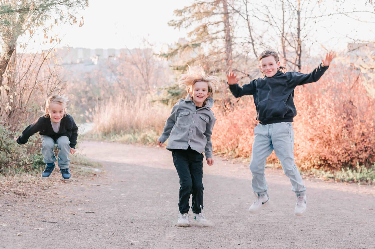 3 young boys jump high in the air. 