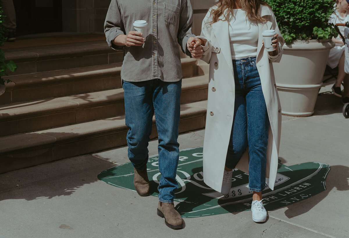 couple walking with coffee during NYC engagement photoshoot, captured by Elsie Goodman, an NYC engagement and couples photographer