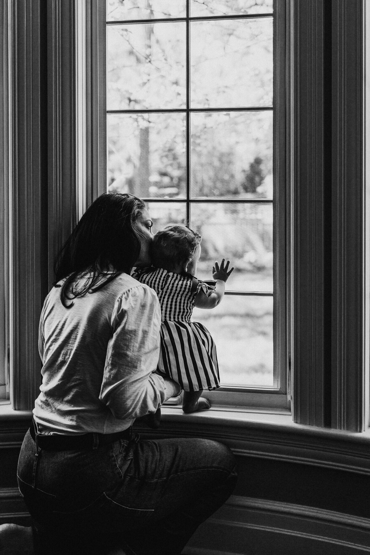 Mother and baby looking out the window in their home