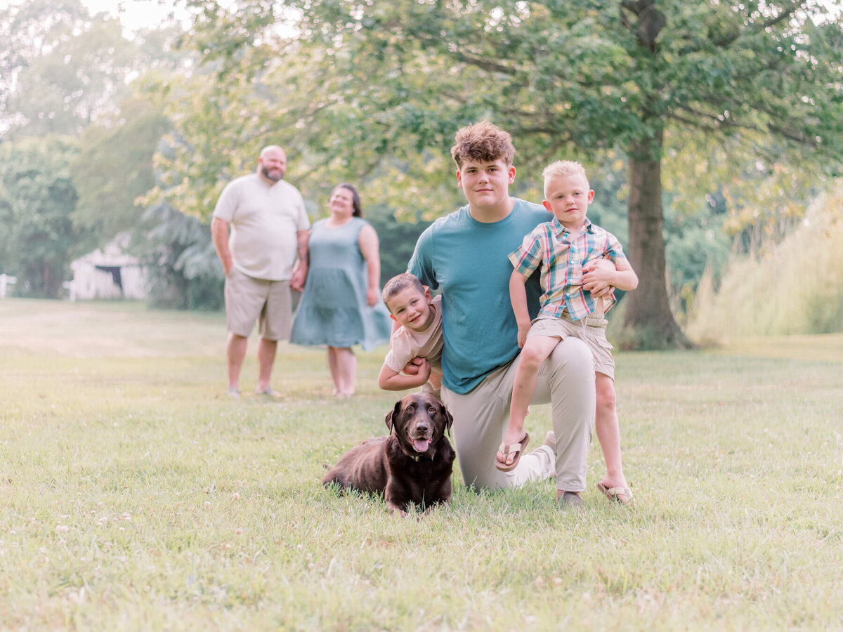 Parents looking at their three young boys and family dog.