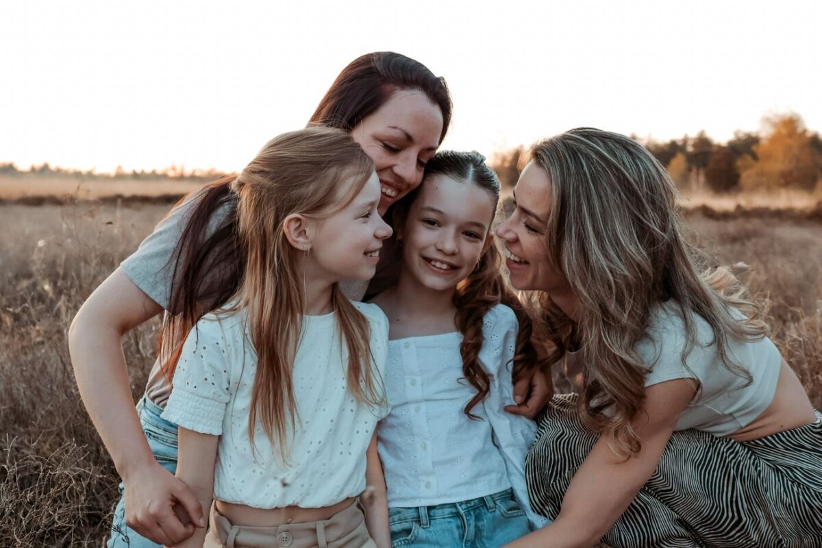 Vrolijke familieportret van moeder en dochters en hun tante tijdens fotosessie in avondlicht