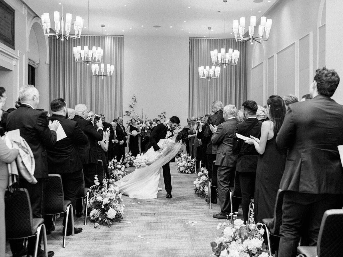 Bride and groom share a kiss down the aisle at their wedding ceremony in Hotel Washington 