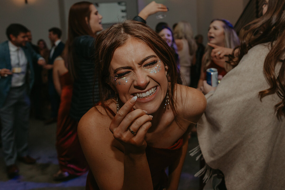 bridesmaid with glitter laughing at wedding reception