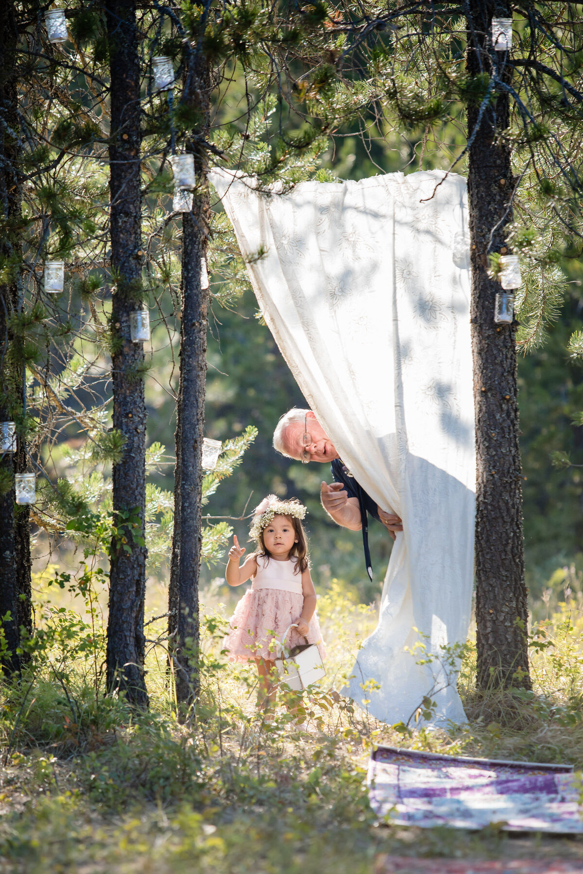 The father of the bride gives a flower girl directions from behind a blind during a wedding ceremony in Coeur d'Alene, Idaho.