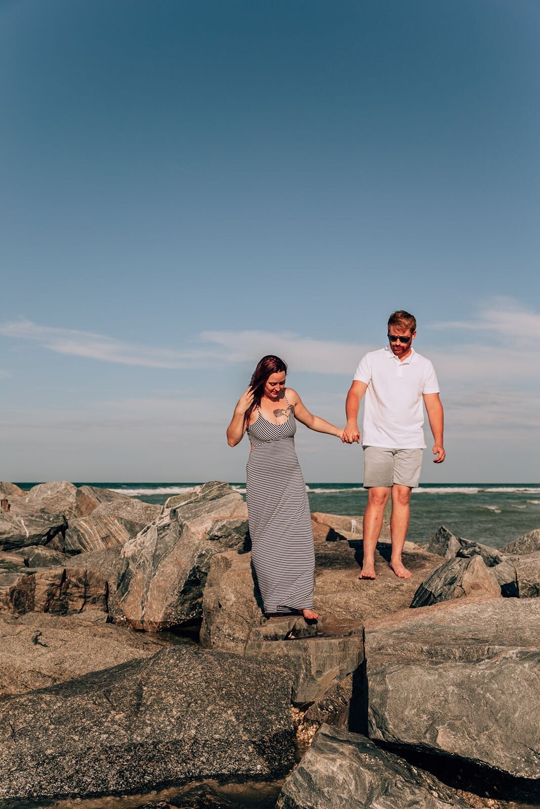 couple walking along the jetty rocks at new smyrna beach