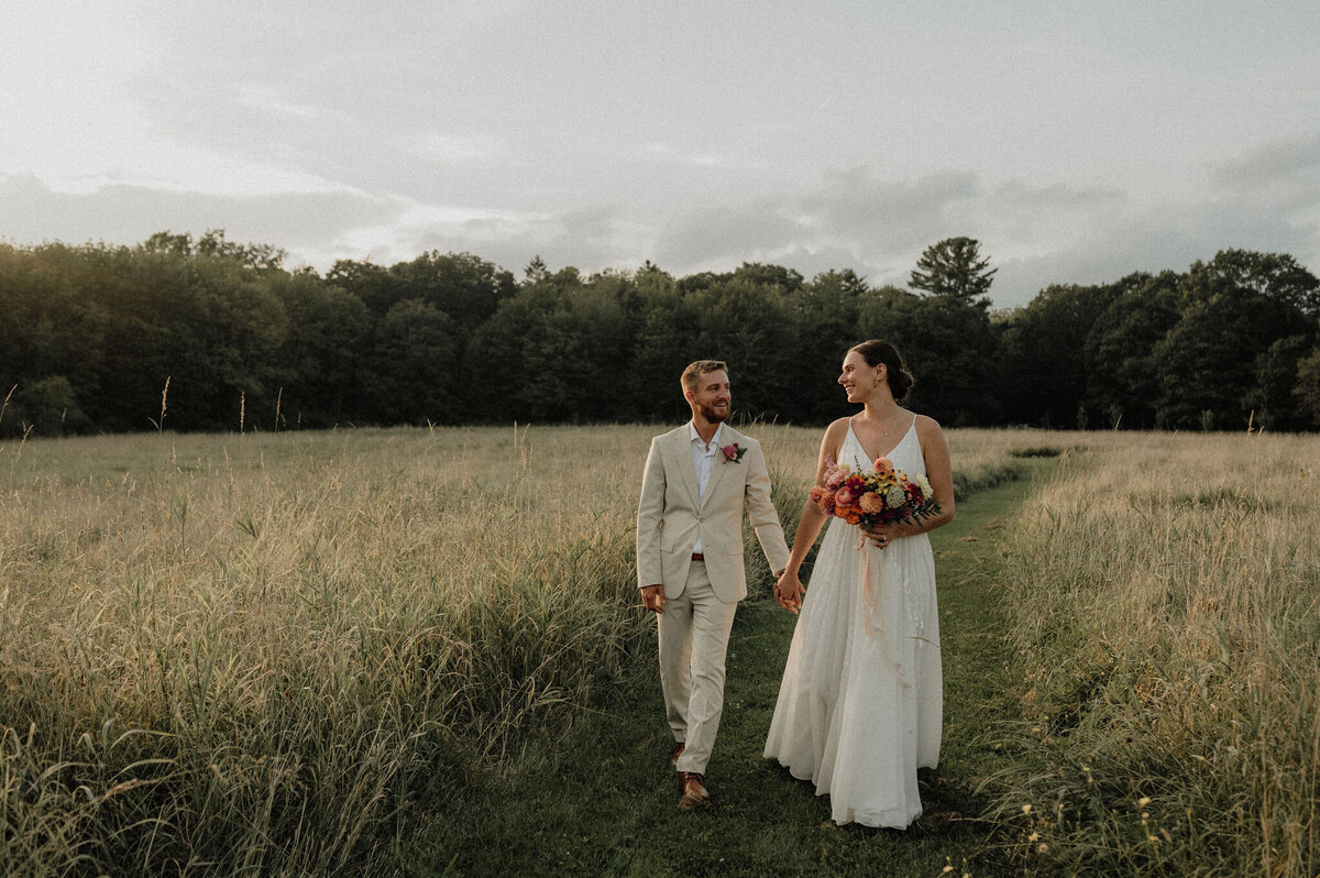 Couple walking in a field after Maine wedding