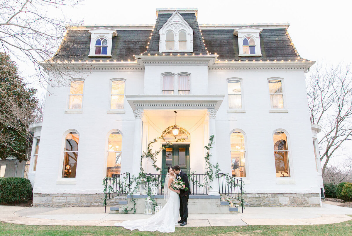 Bride and Groom standing in front of Ceresville Mansion in Frederick Maryland during winter wedding. Captured by Bethany Aubre Photography.