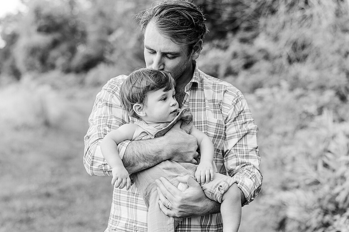 black and white of father kissing son during Family photo session with Sara Sniderman Photography at Heard Farm in Wayland Massachusetts