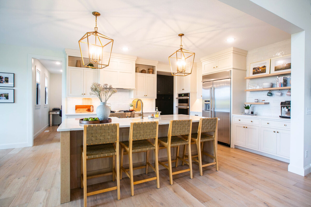 Open kitchen with white cabinets, large island, and quartz countertops in an Otsego custom home