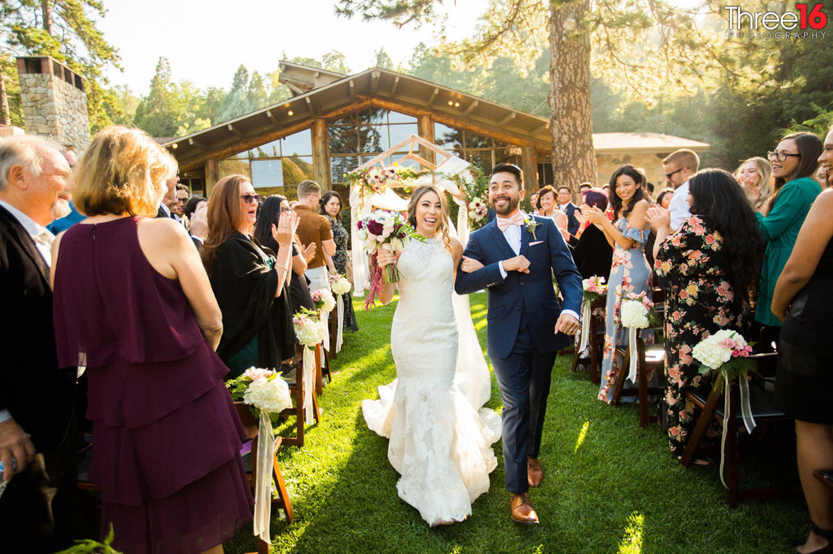 Bride and Groom strut down the aisle after saying their I Do's amongst wedding guests