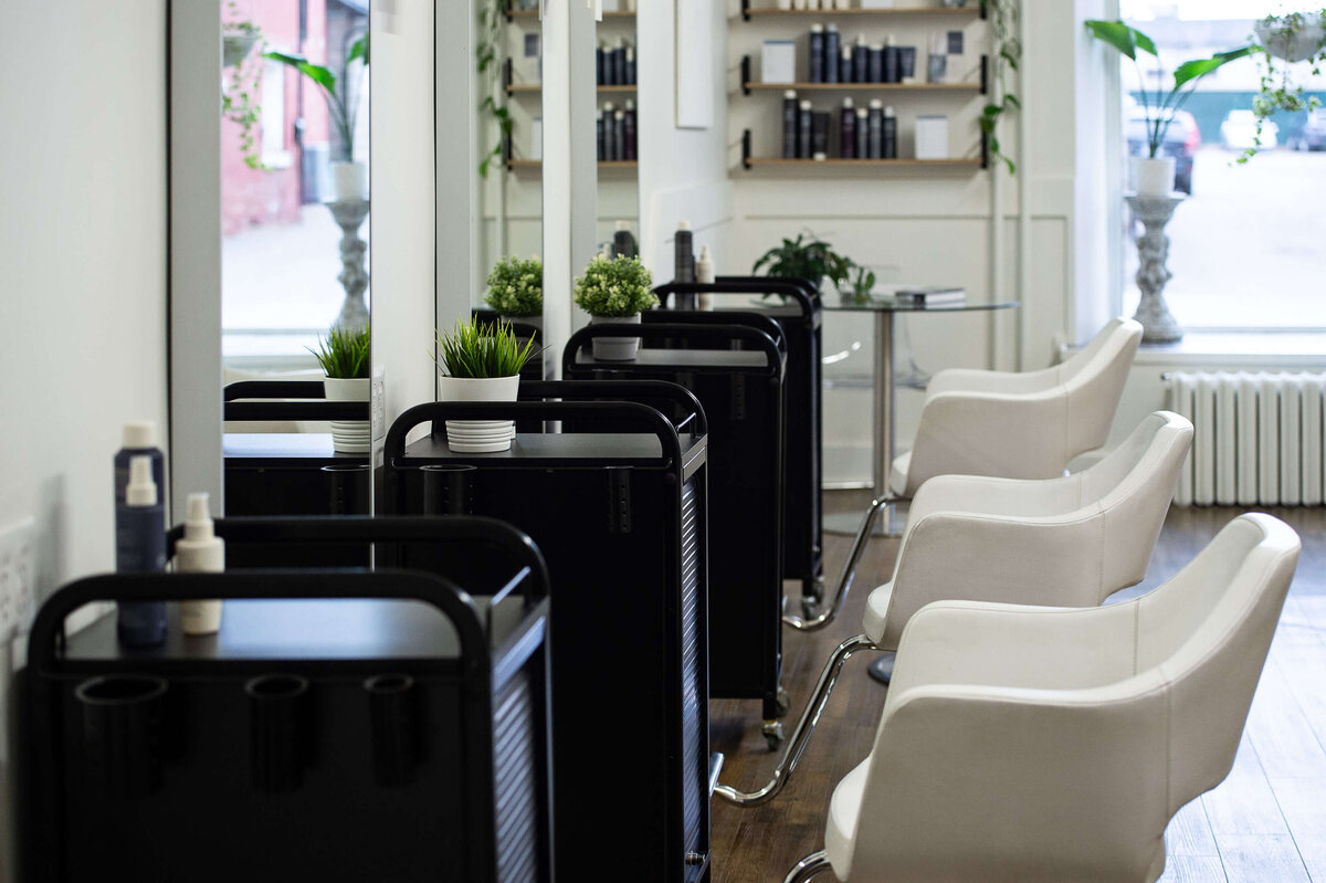 an interior photo of Richarddson Hair Design showing the styling stations with black drawers and white chairs in a row.  Captured on site by Ottawa branding photographer JEMMAN Photography