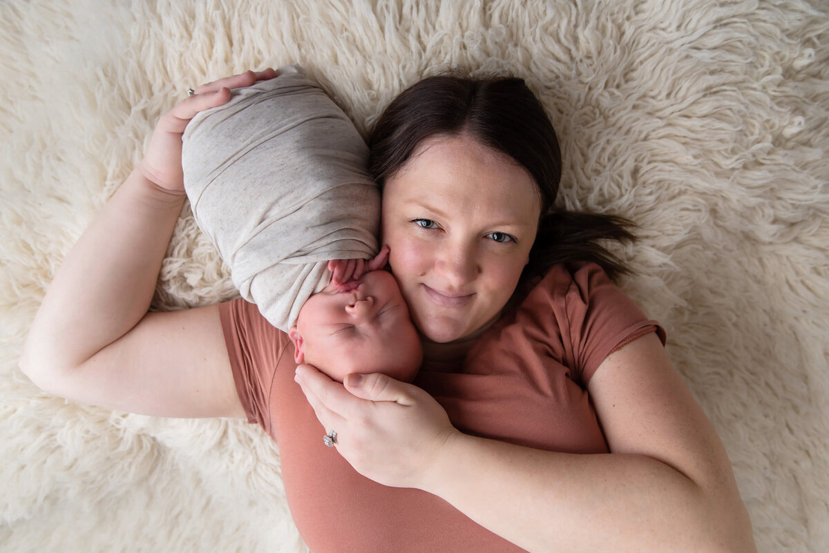 mom laying on the floor with her newborn baby boy for their newborn photos in Burlington, Ontario.