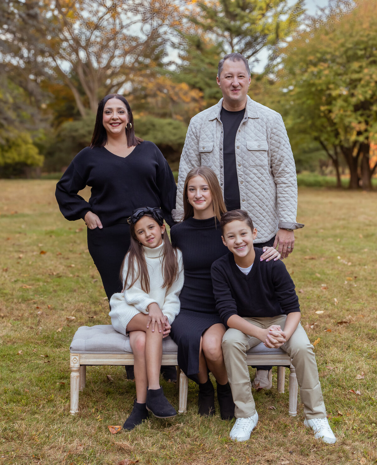 Family of five smiling at the camera during an outdoor photo session near Clifton, NJ