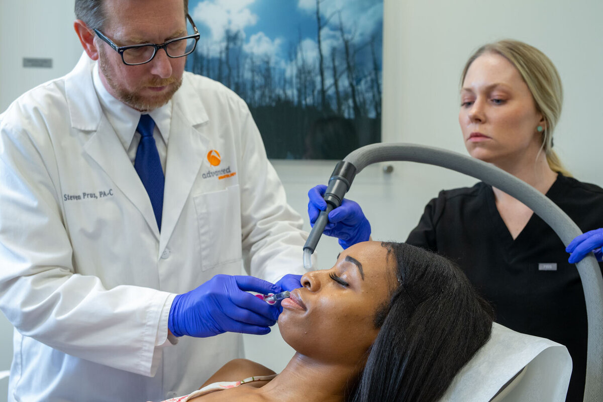 A woman is getting a treatment from a doctor who is wearing blue gloves