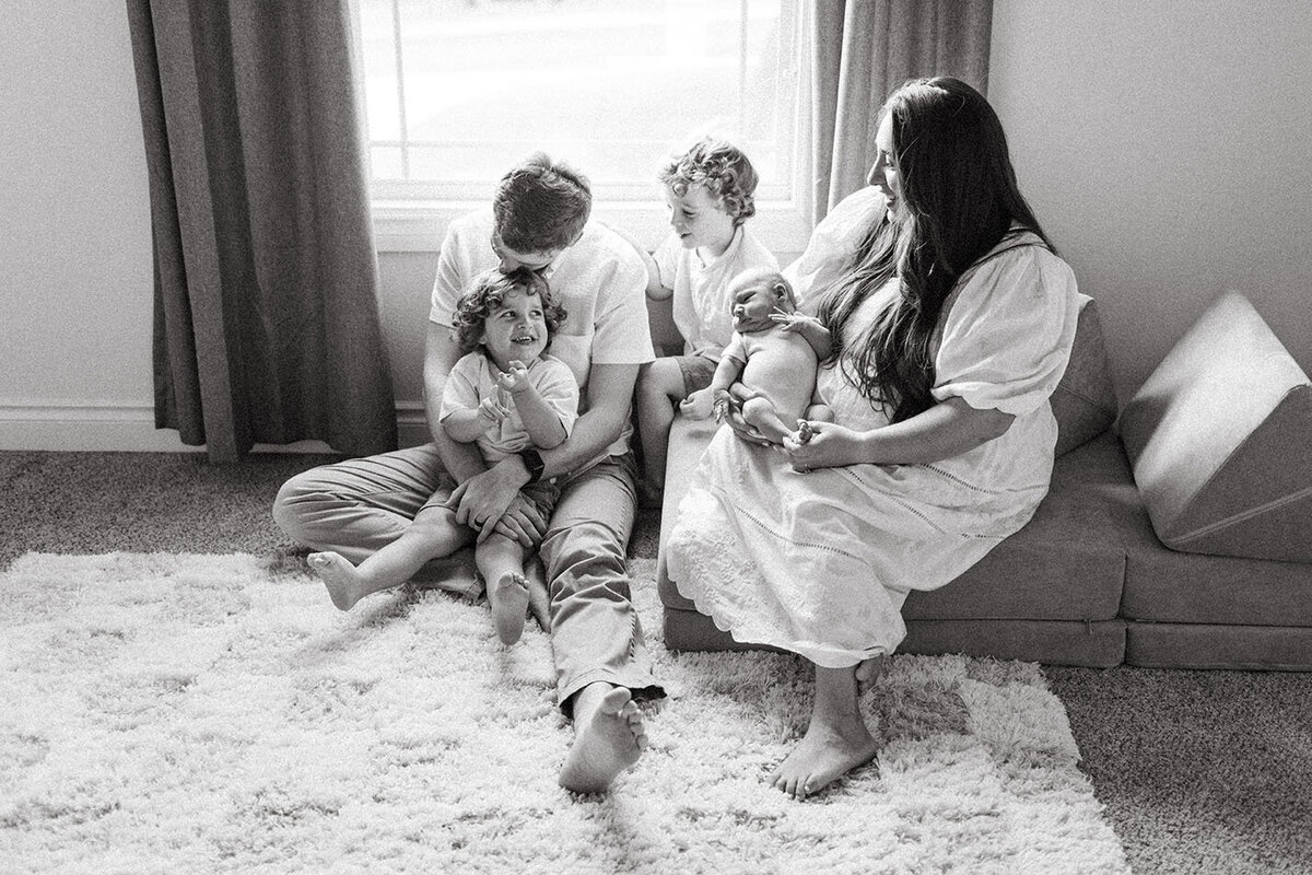 Black and white candid family moment indoors - Sara James San Antonio lifestyle photographer creates artistic documentary family images capturing authentic connections in comfortable home environments