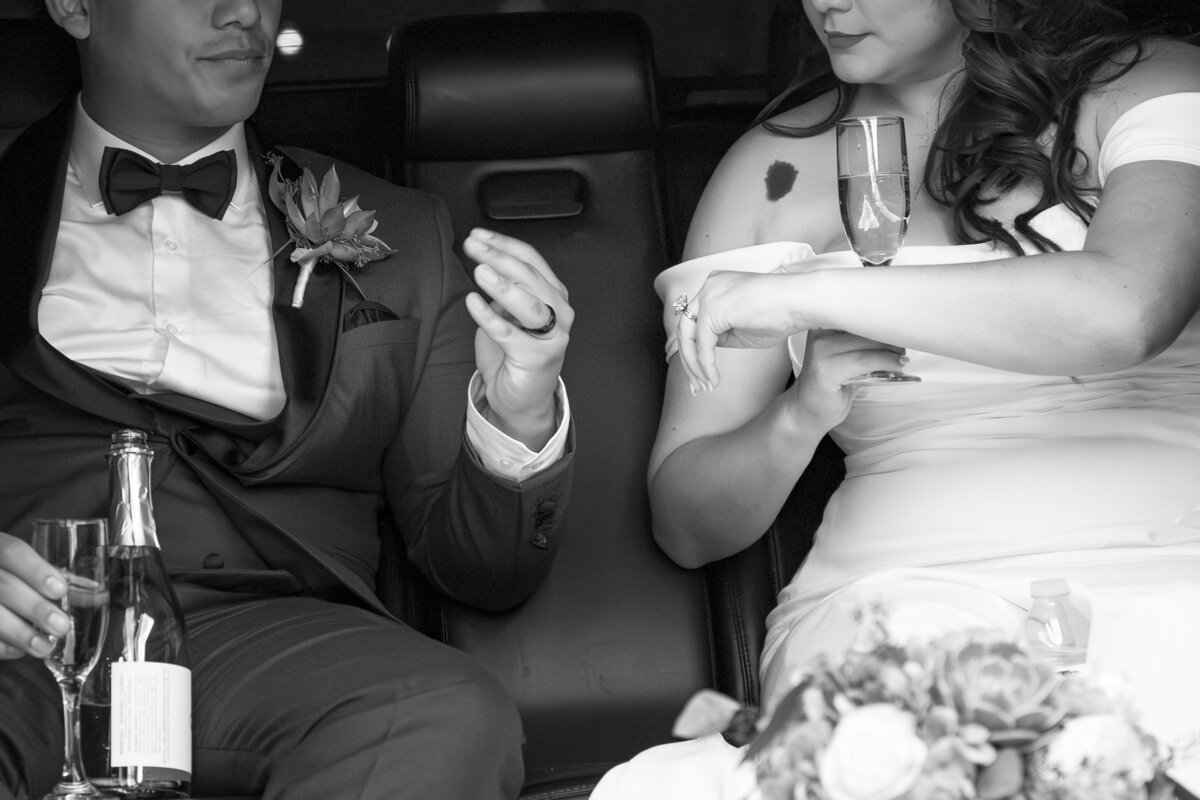 Newlyweds sitting in a car drinking champagne together