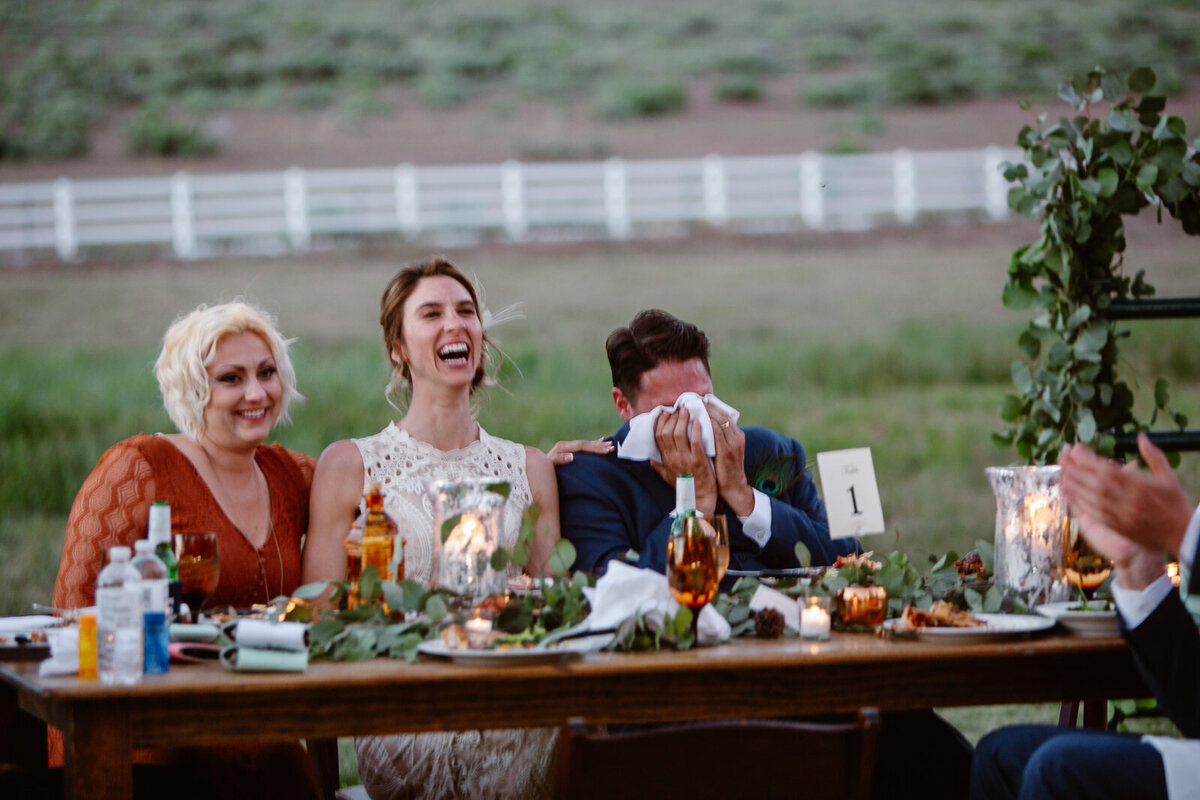 A couple laughs and cries at the table during their wedding day.