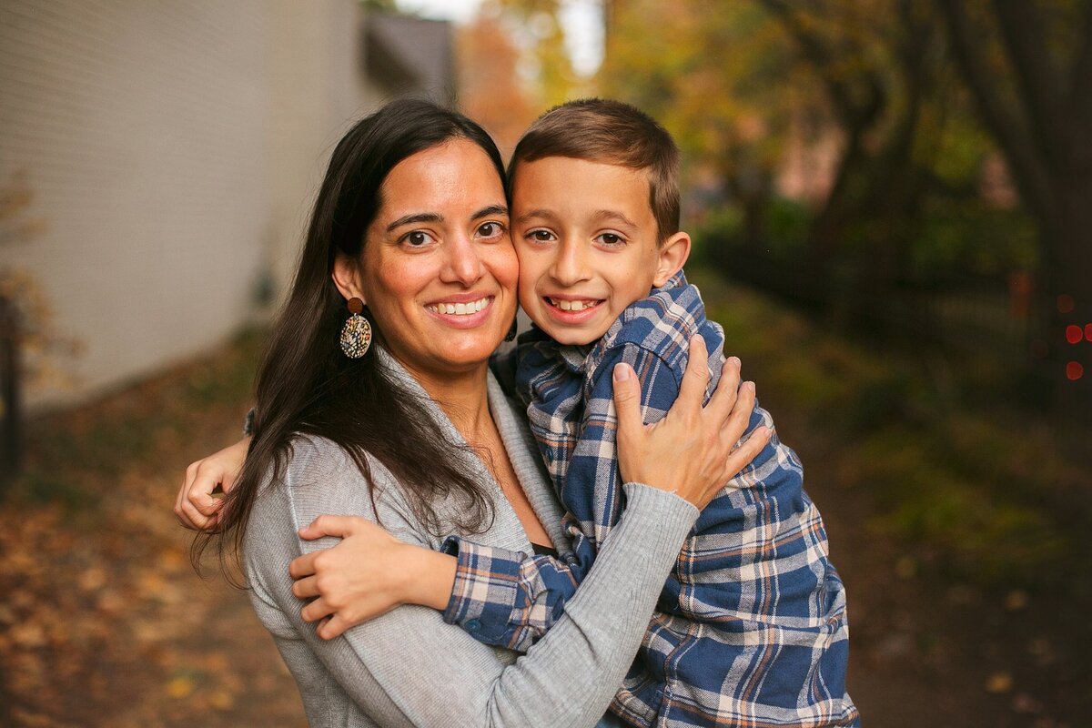 A-mother-hugging-her-son-as-they-smile-ona-quaint-street-in-the-east-side-of-indy-in-the-woodruff-place-neighborhood-during-a-warm-family-photo-session