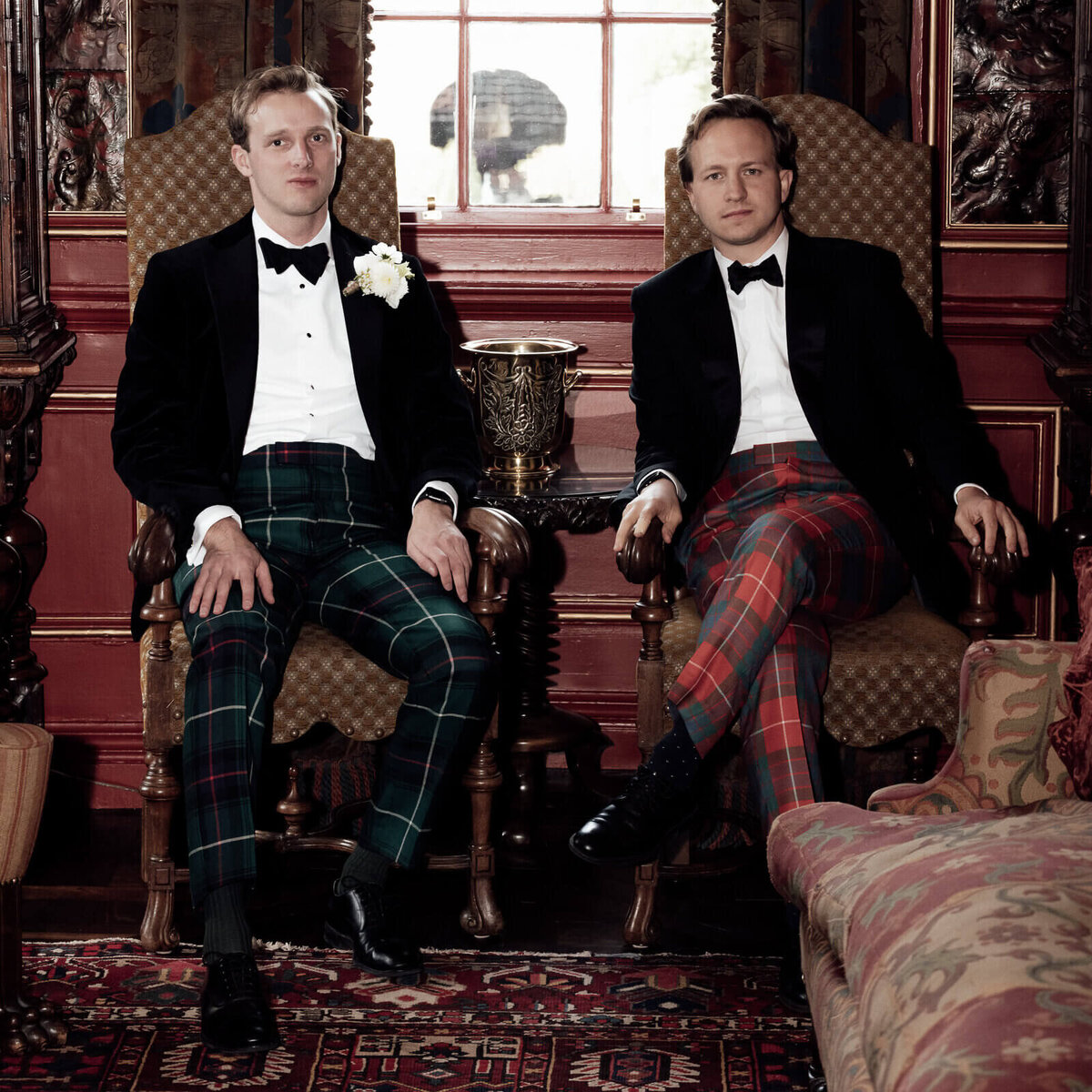 Groom and his best man in tuxedos and troos sit down before the wedding day.