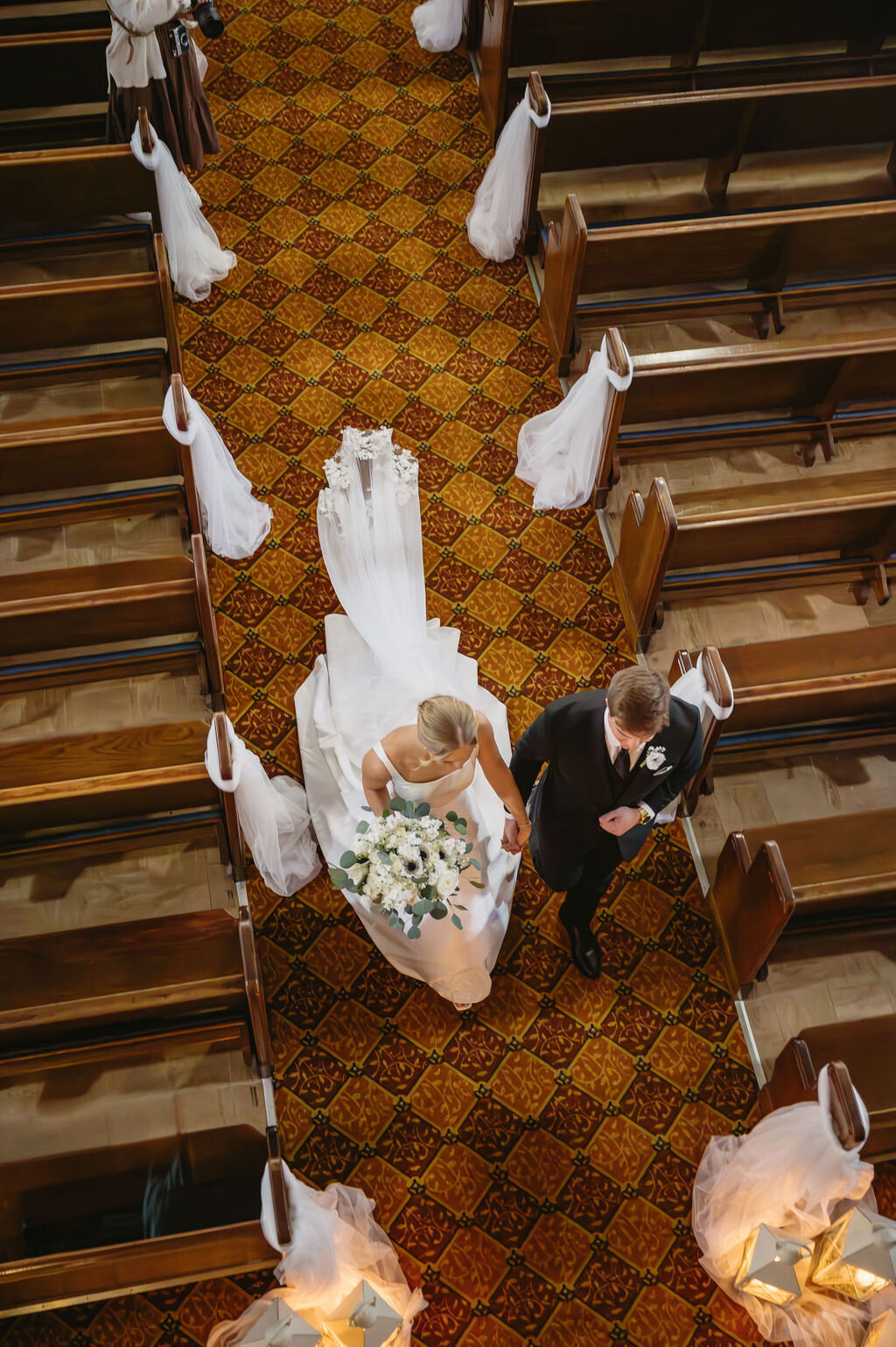 overhead view of bride and groom walking down the church aisle