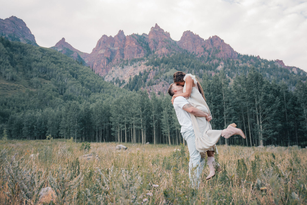 Couple cuddling on a quiet mountain road during their Aspen engagement photos