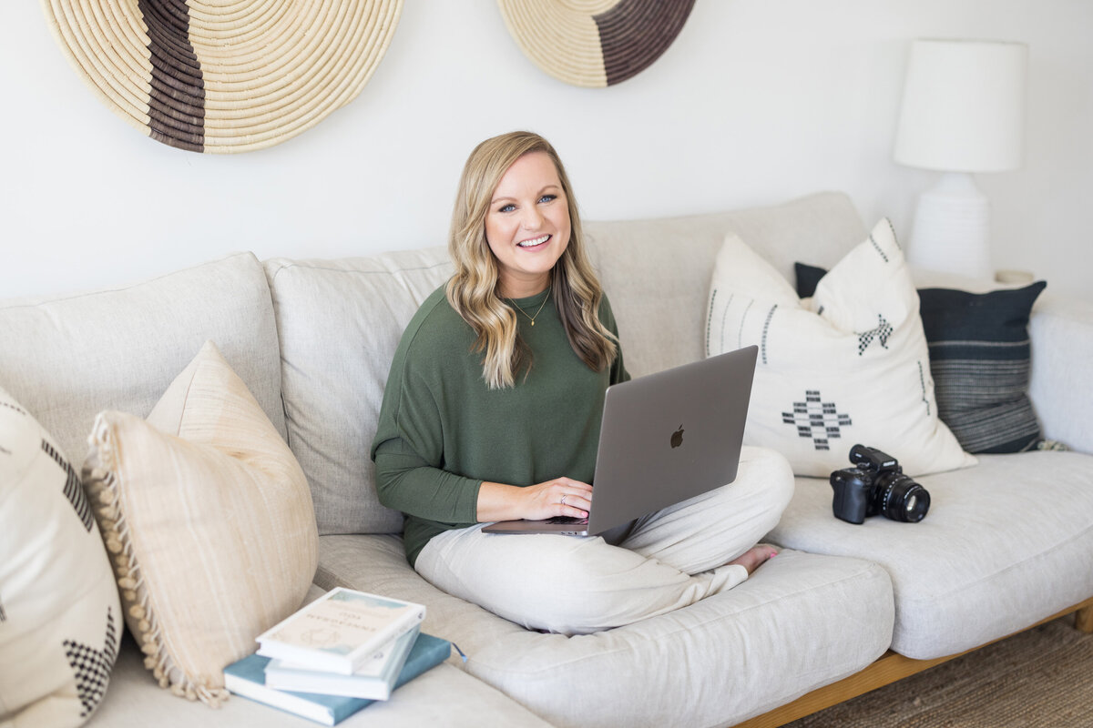Krista Marie, a brand photographer for women, smiling at the camera while on her laptop