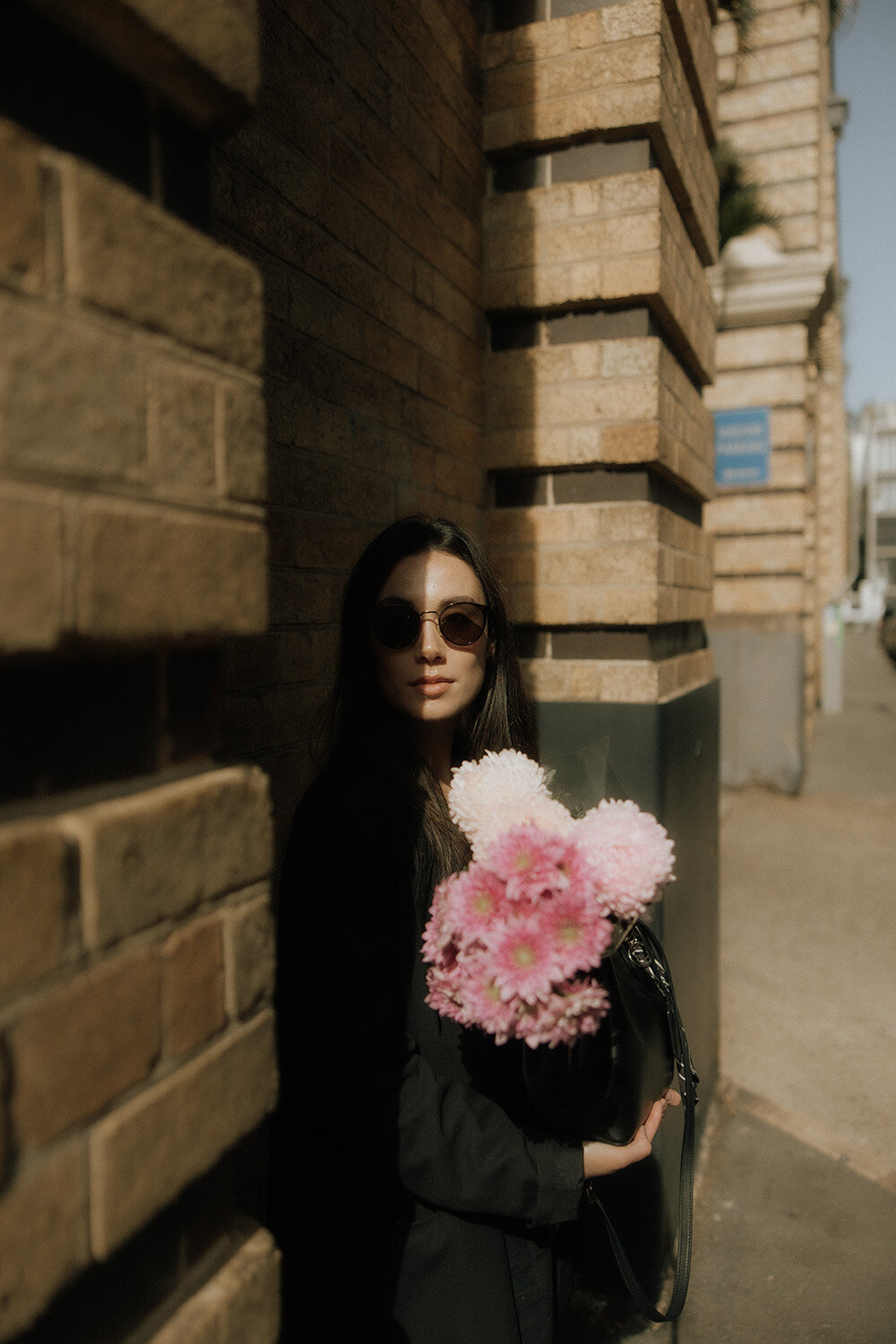 Unique brand image of a woman with oversized flowers in hand, caught in shadow by Sunshine Coast branding photographer for an editorial edge.