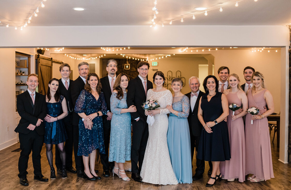 Family and wedding party stand facing the camera in a line as denver wedding photographer takes a photo of them