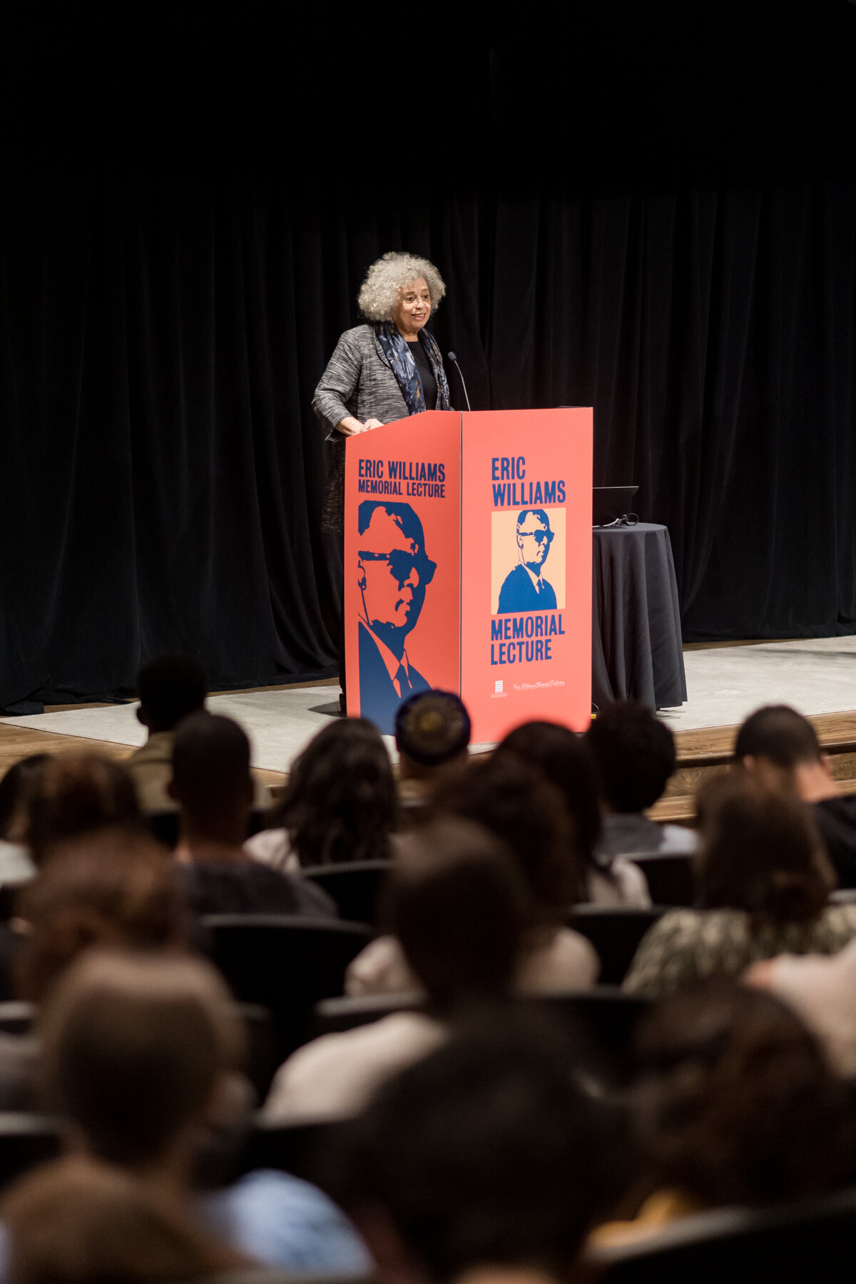 a woman stands in front of a podium, speaking to a crowd