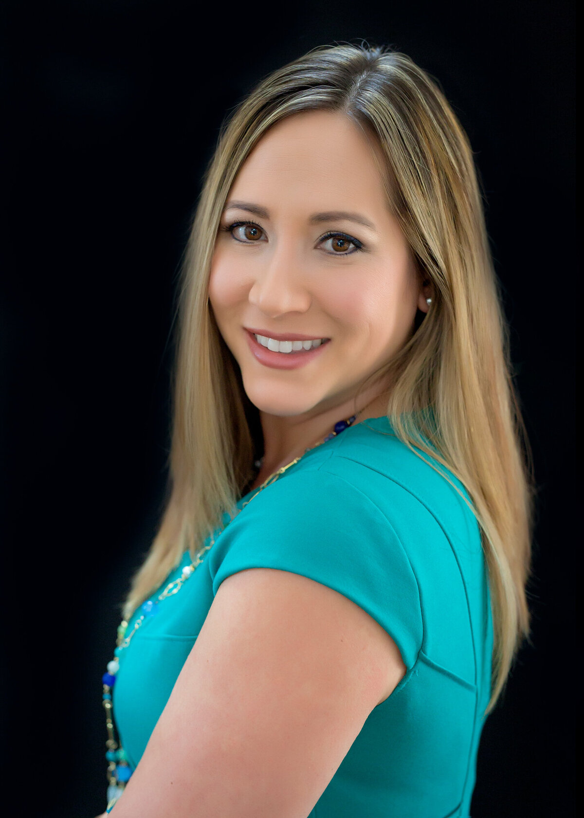 Female headshot client cropped close with a teal top while smiling at the camera