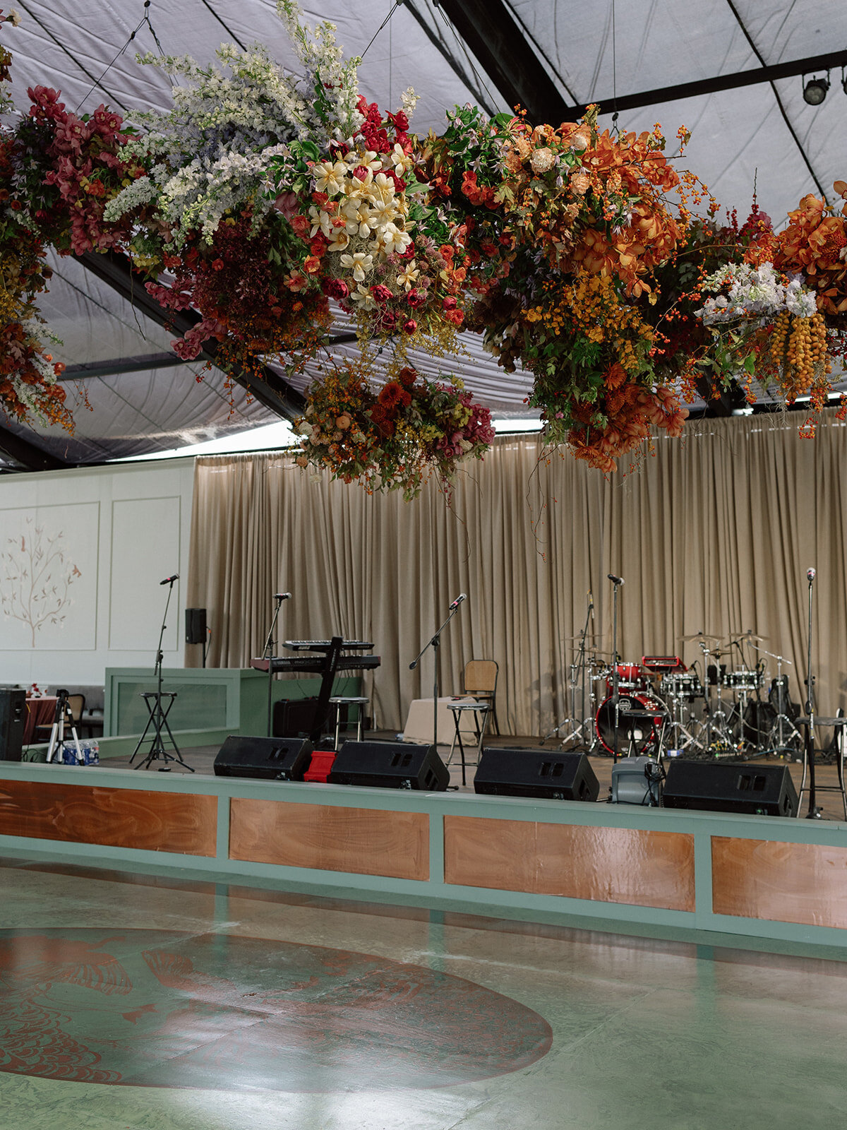 Interacting and sculptural floral clouds hang over the dance floor and bars of this fall wedding reception in Tennessee. Clear top tent build out for fall wedding reception in Tennessee hills.  Product clustered floral clouds in a tasteful fall color palette of copper, ruby, gold, burgundy, rust, and lavender. Orchids, bittersweet berries, butterfly ranunculus, and tulips are highlighted. Unique floral design with flower forward large scale installations. Design by Rosemary & Finch Floral Design in Nashville, TN.