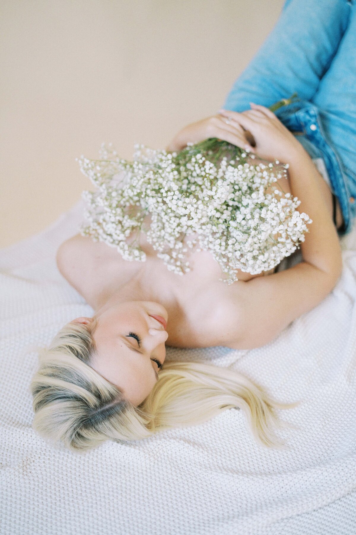 pregnant mom holding flowers over breasts during maternity photos
