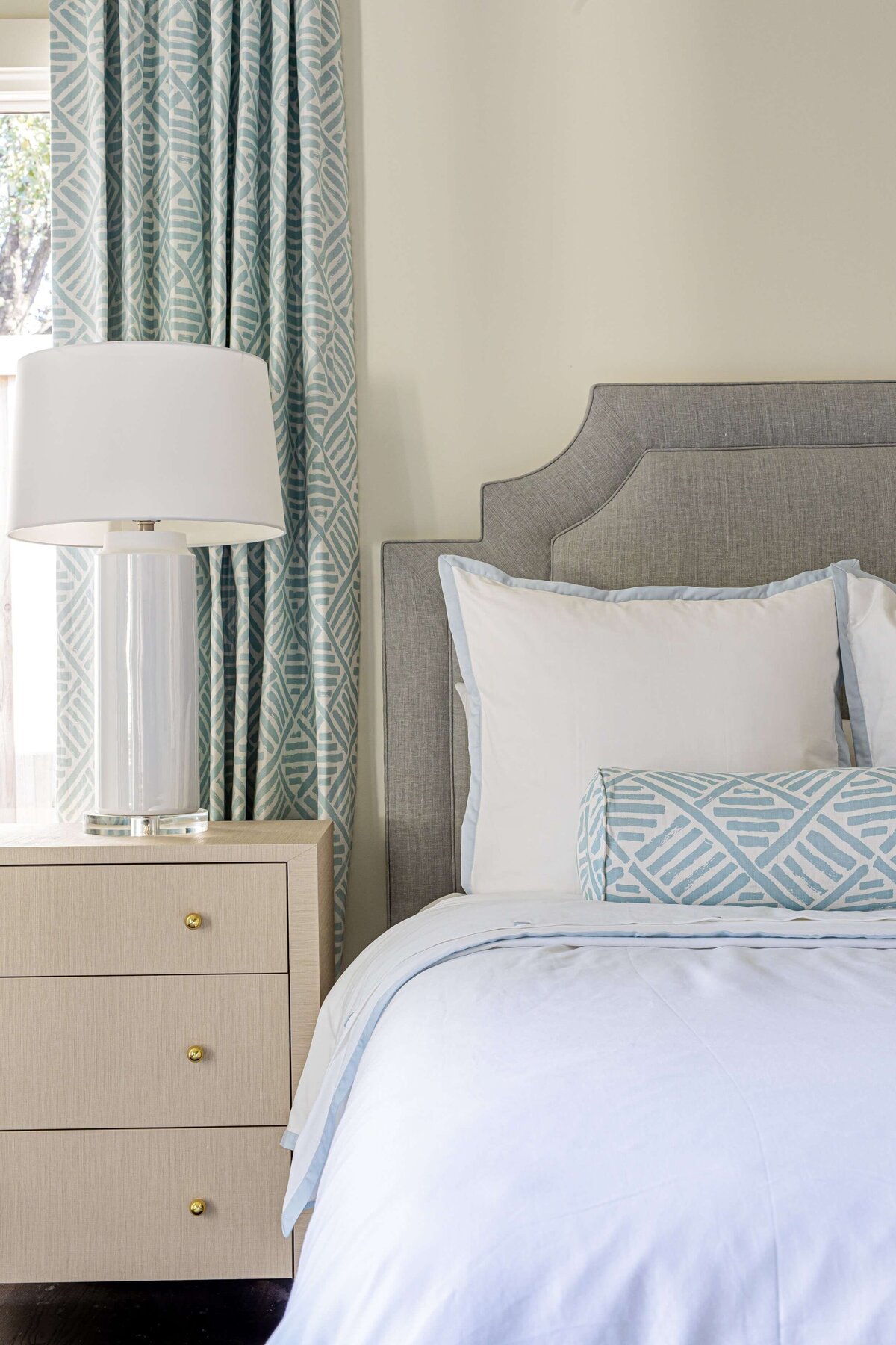 oyster creek studios highland park home white bed with light wooden sidetable and light blue curtains