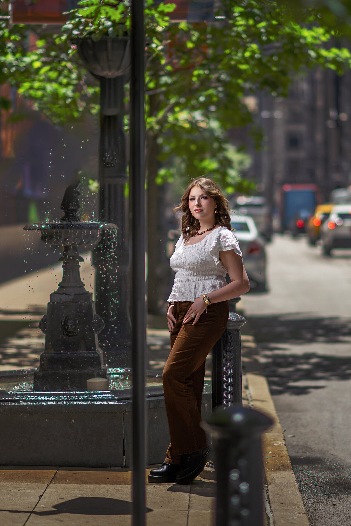 An image from an Iowa Senior Photographer leaning on a post by a fountain in the street