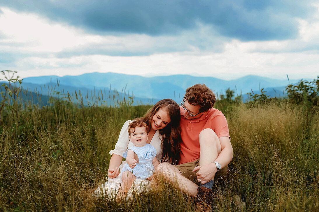 Family sits together on a mountain top on the Blue Ridge Parkway during Family Photos in Asheville, NC.