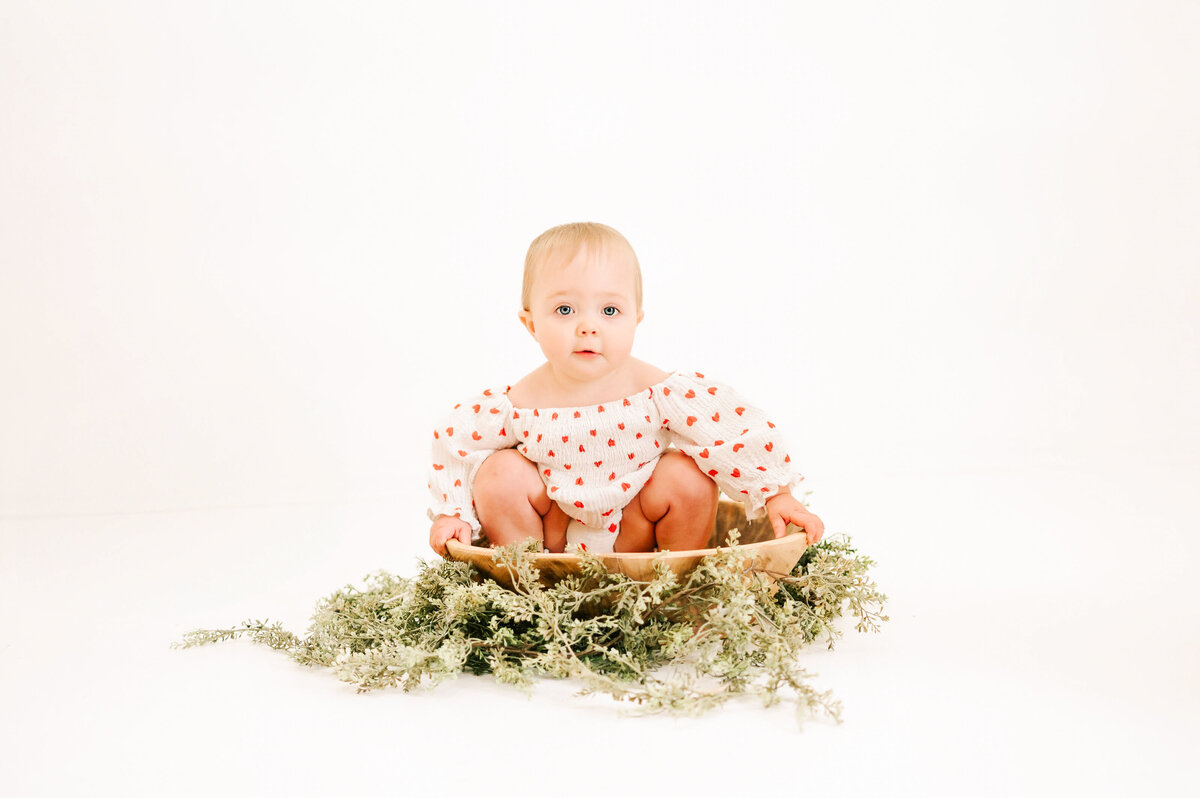 baby girl sitting in wooden bowl during Springfield MO kids 1st birthday photography session